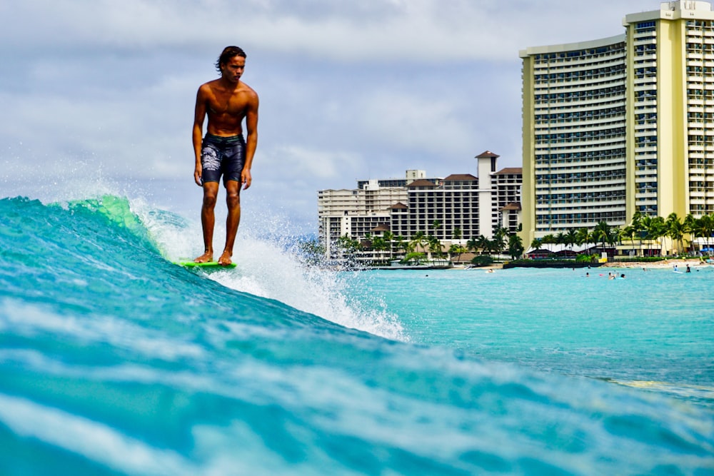 man in black shorts surfing on sea during daytime