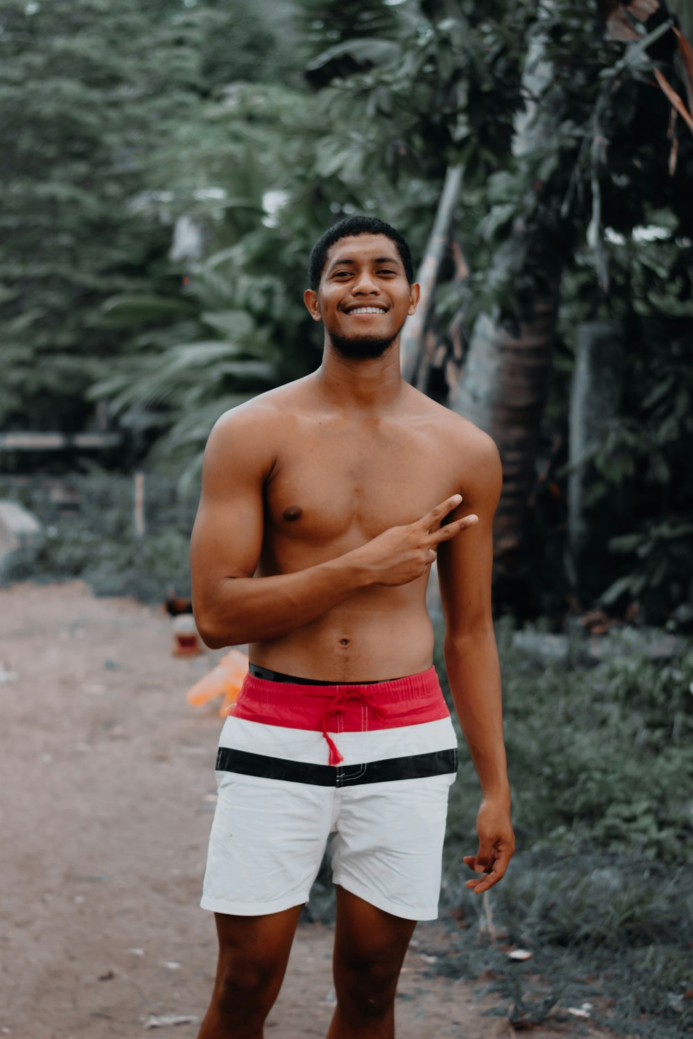 topless man in white shorts standing on dirt ground during daytime