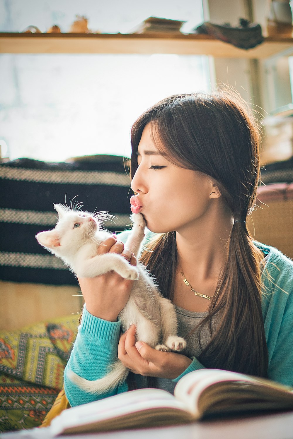 woman in green and blue striped shirt holding white cat