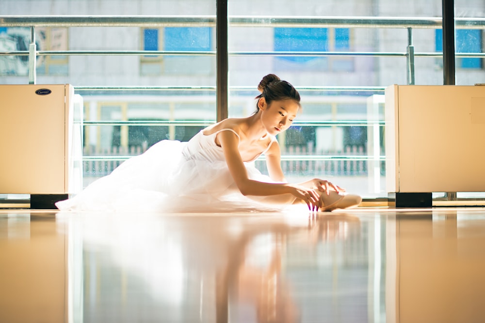 woman in white spaghetti strap dress sitting on floor