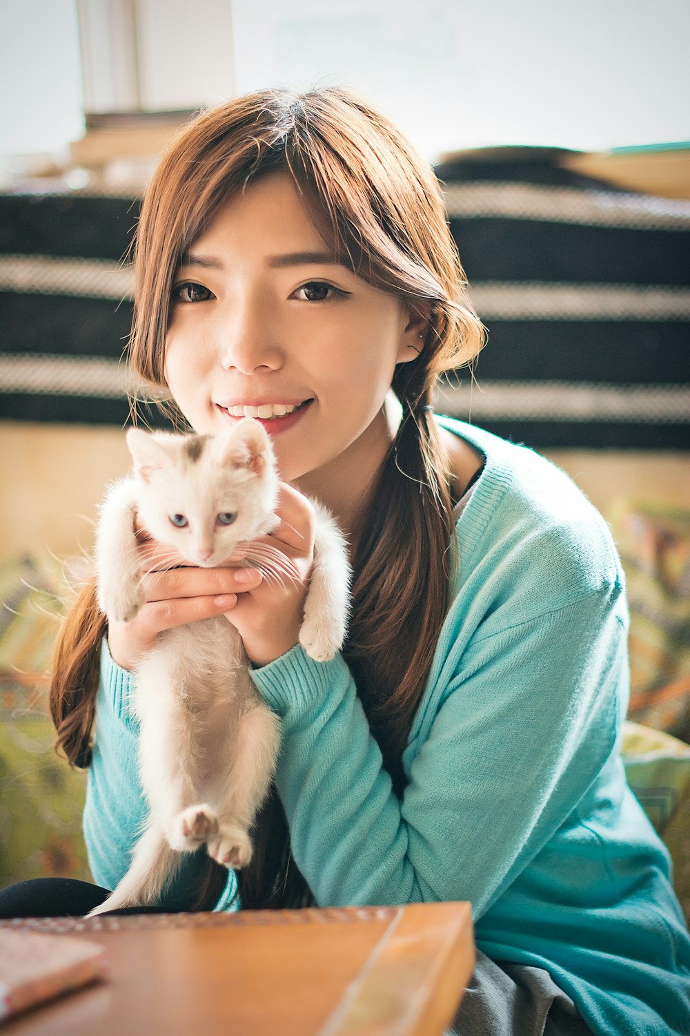 woman in teal sweater holding white kitten