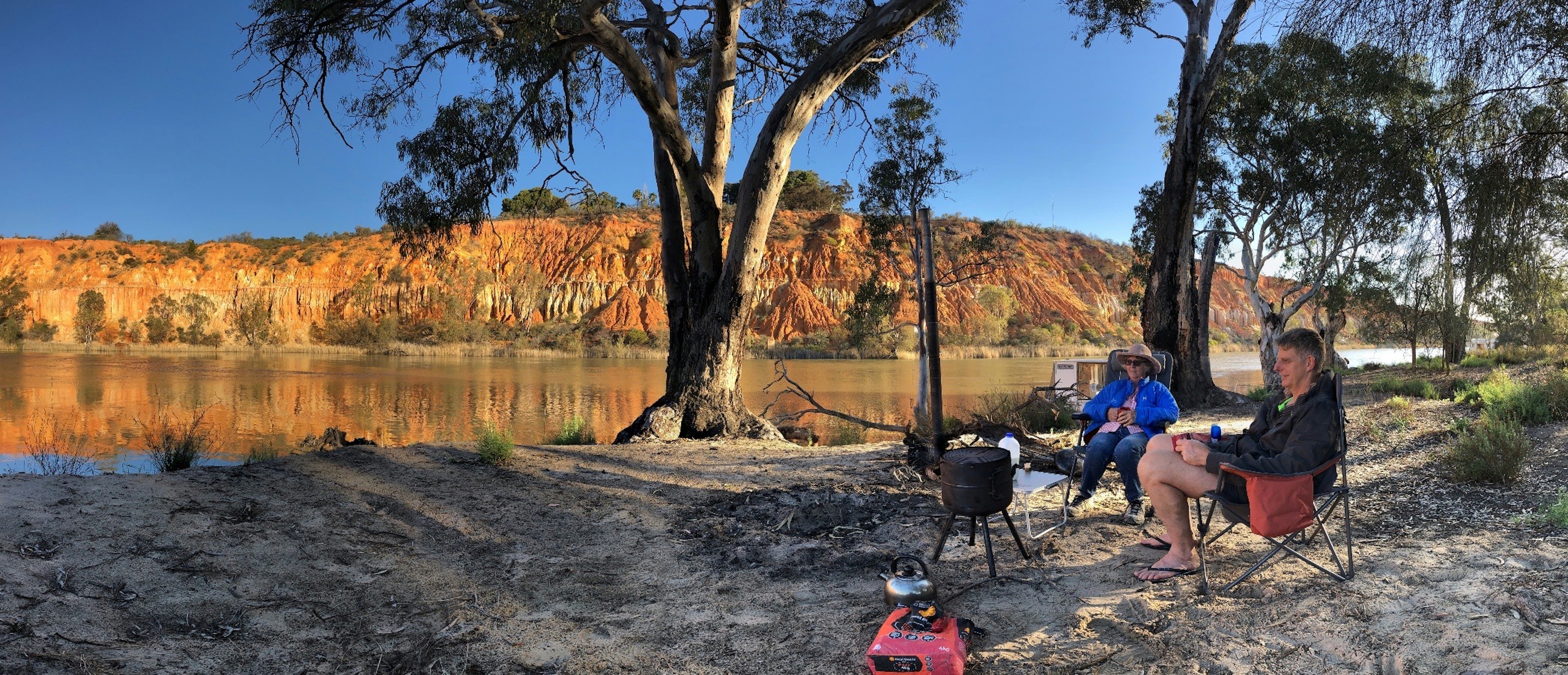 red and black motor scooter near brown tree and body of water during daytime