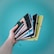 A hand holding several colorful notebooks with elastic closures against a turquoise backdrop. The notebooks are in various colors including black, blue, green, and yellow.