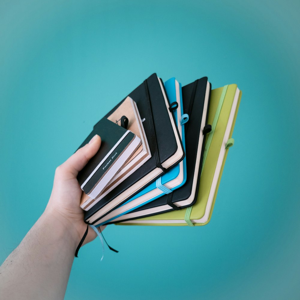 person holding green and black books