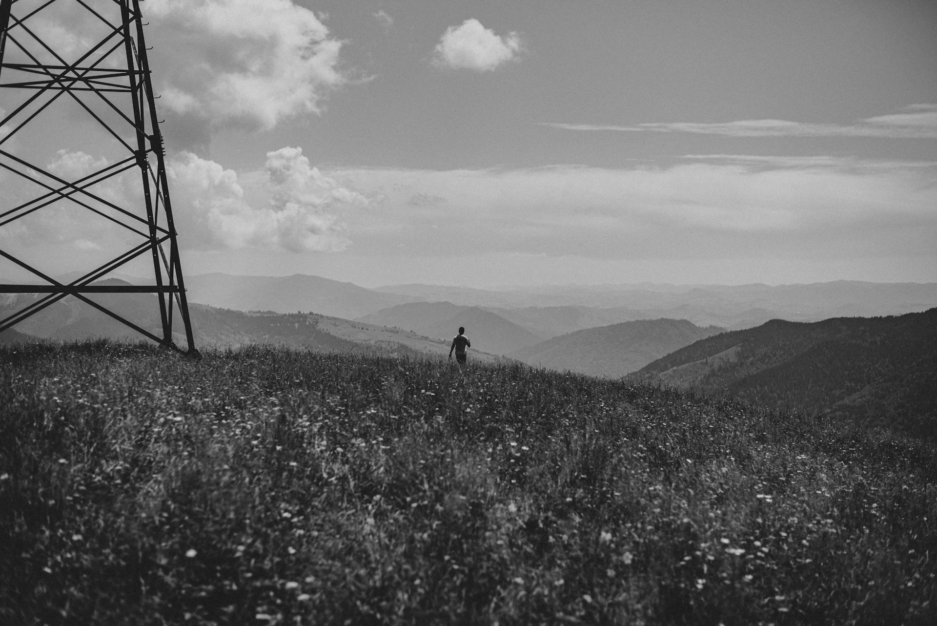 grayscale photo of man walking on grass field