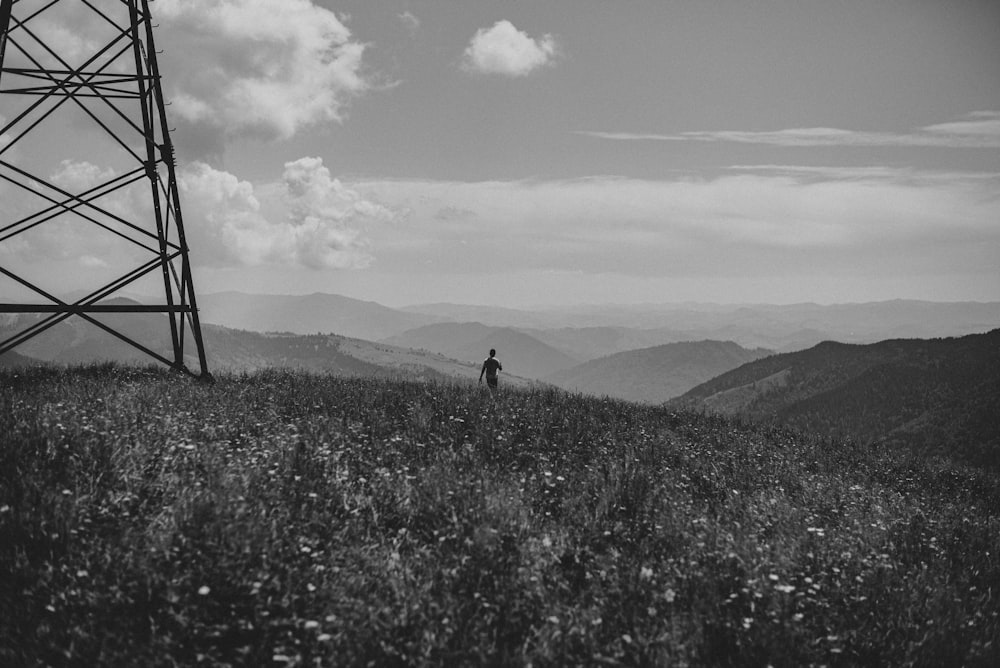 grayscale photo of man walking on grass field