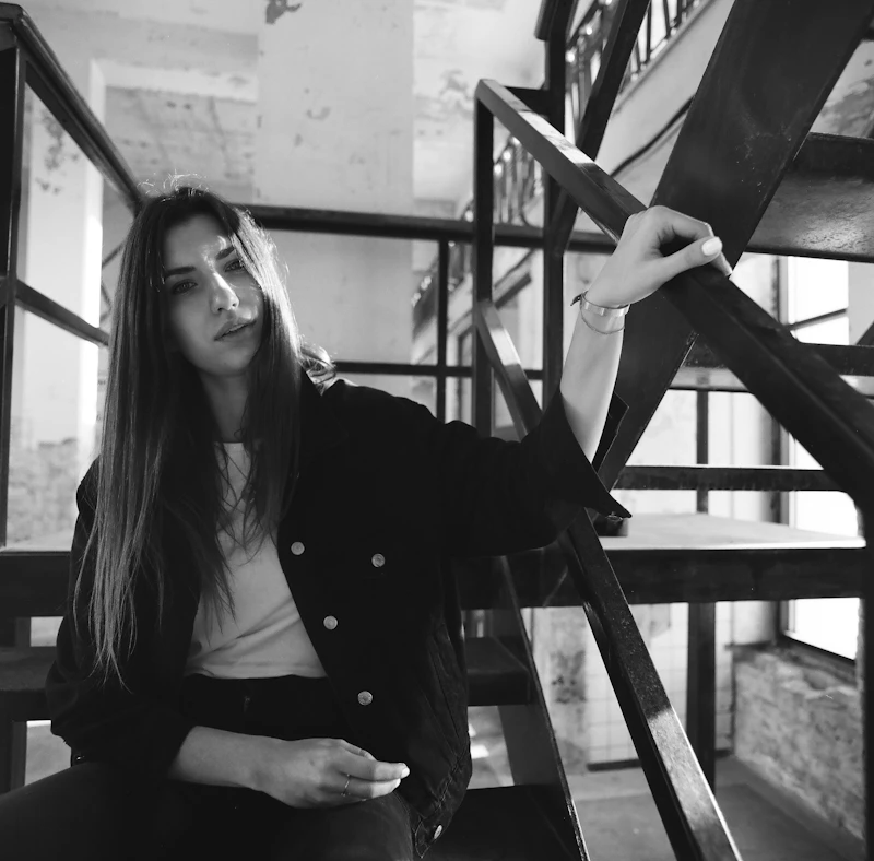 Woman in a black coat sitting on stairs