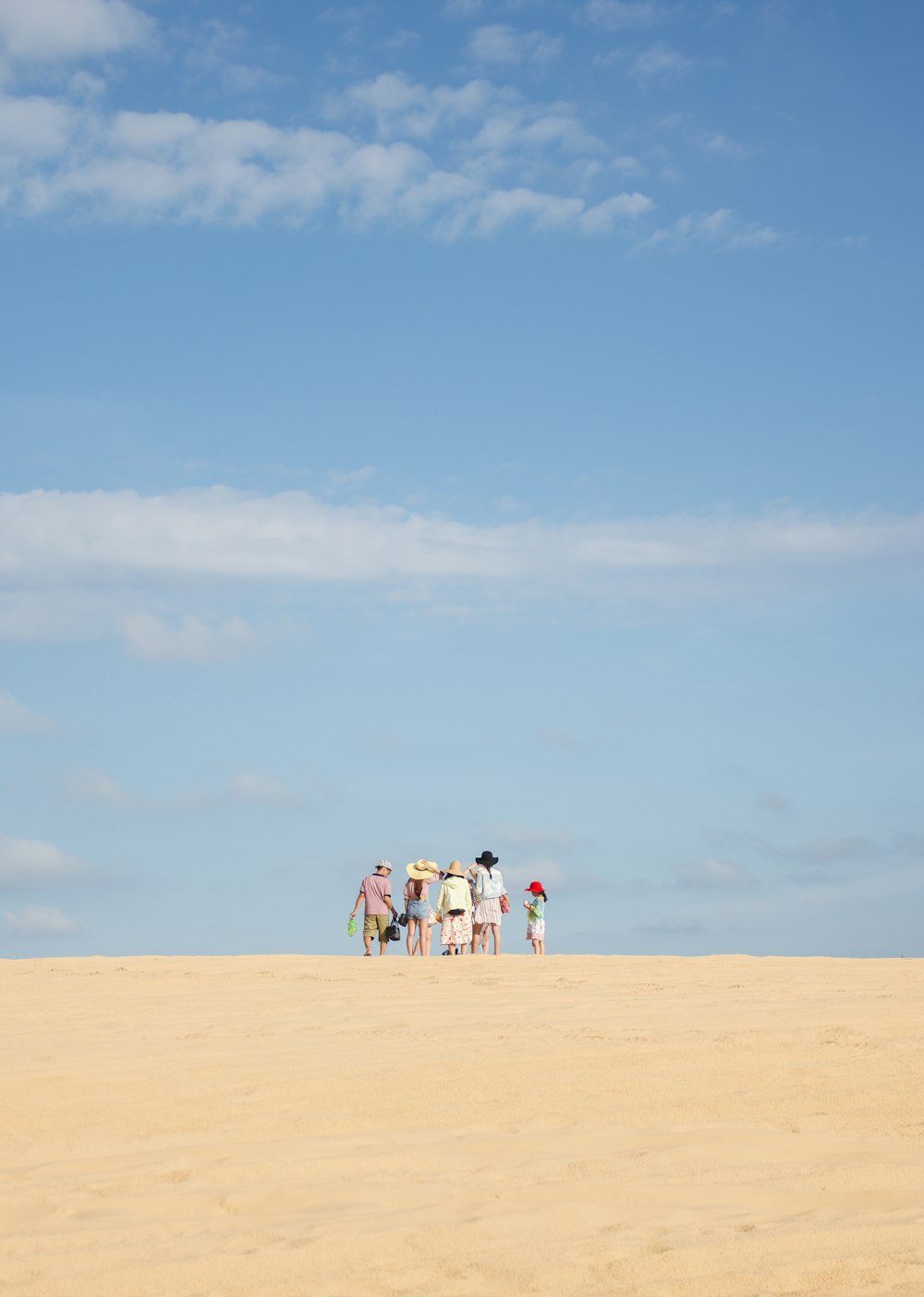 people walking on brown sand under blue sky during daytime