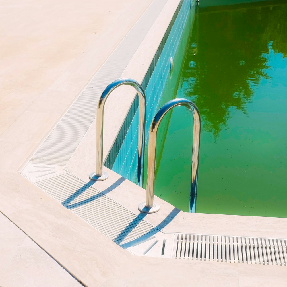 white metal pool ladder beside swimming pool