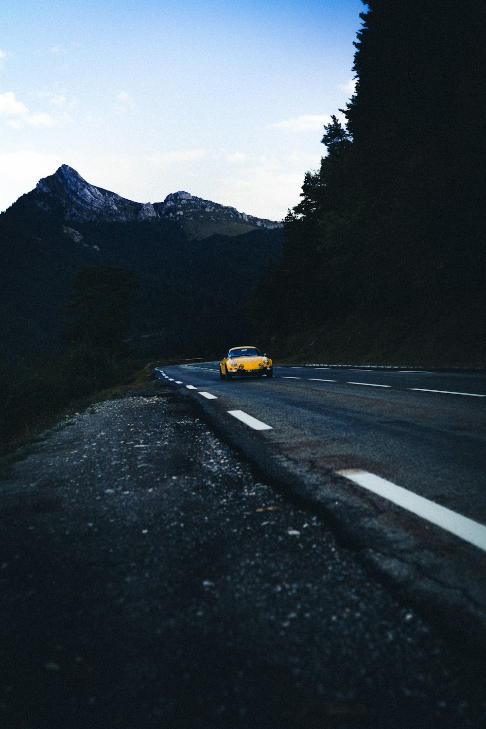 yellow car on road near green trees and mountain during daytime