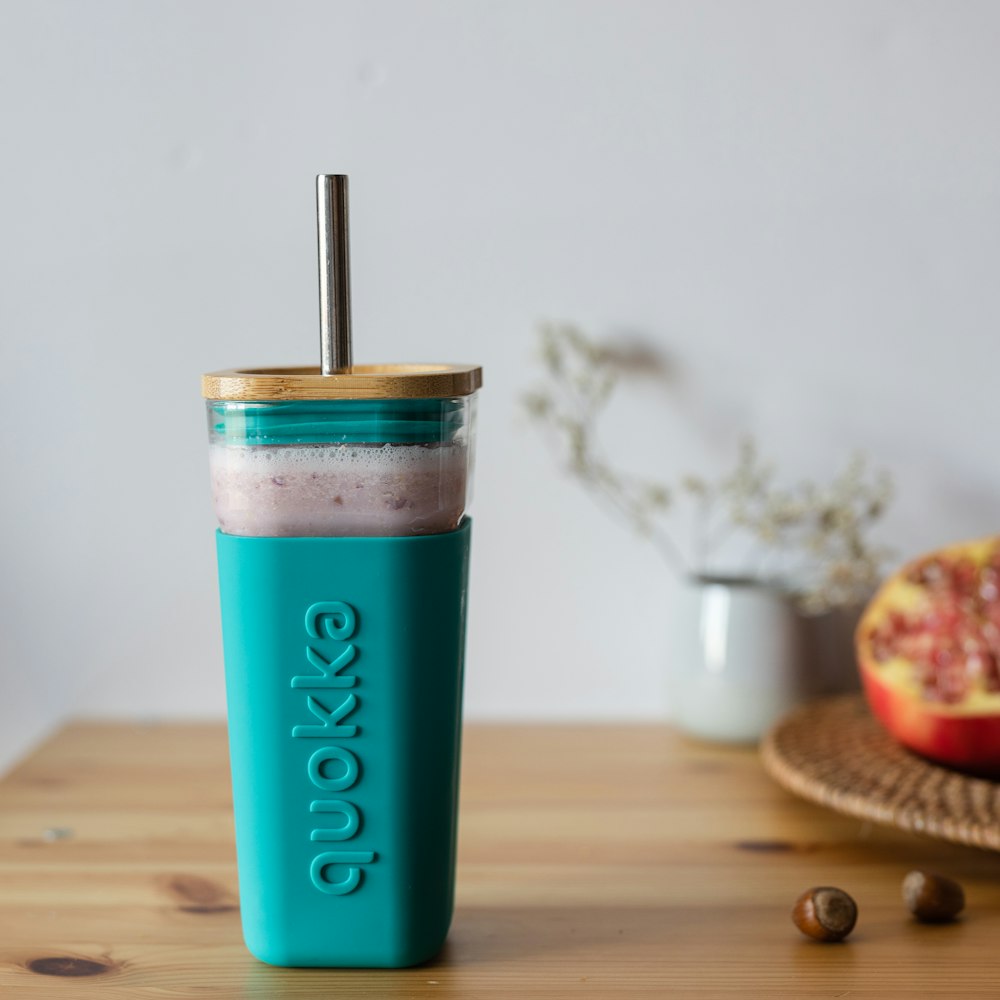 teal and white plastic cup on brown wooden table