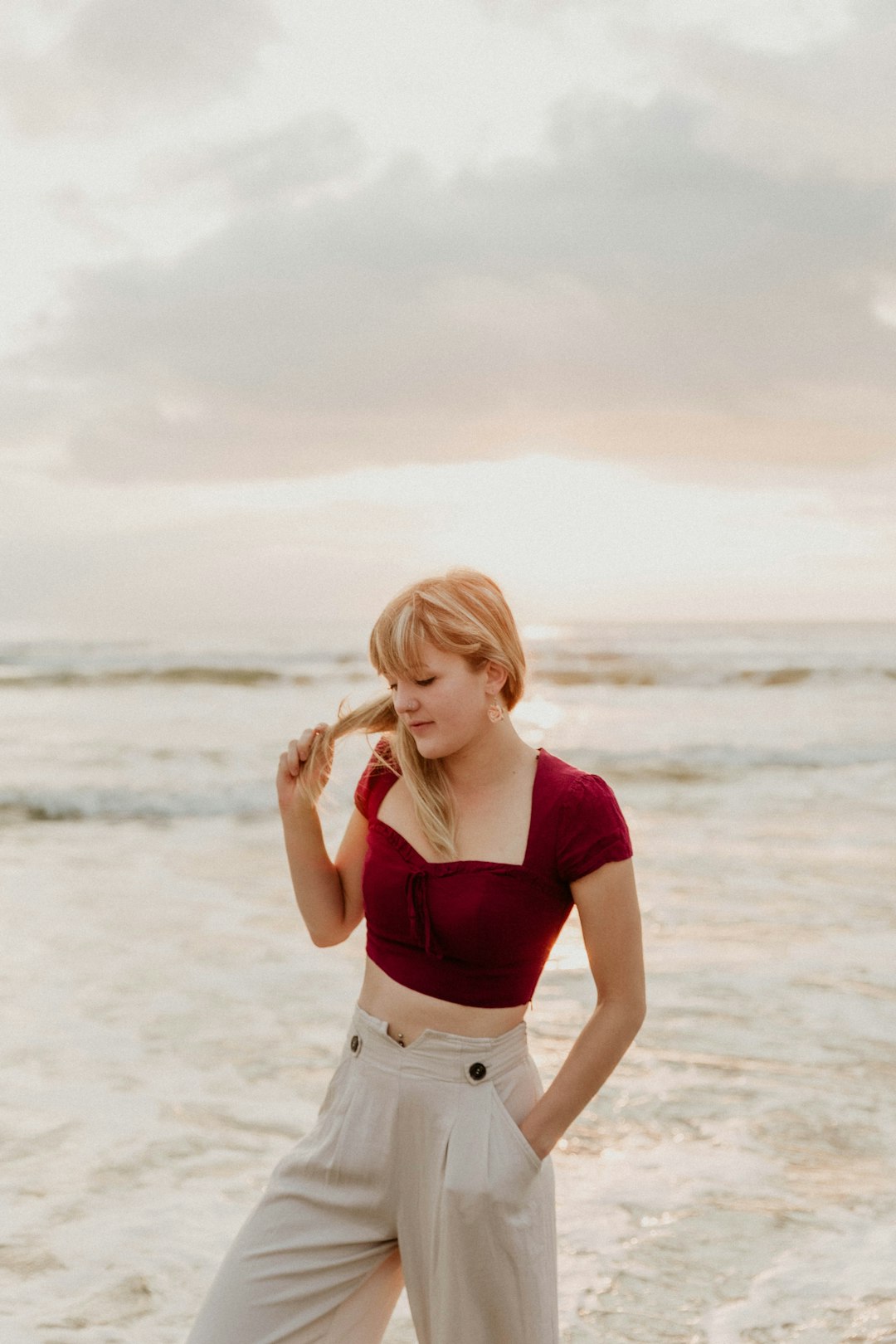 woman in red crop top and white shorts standing on beach during daytime