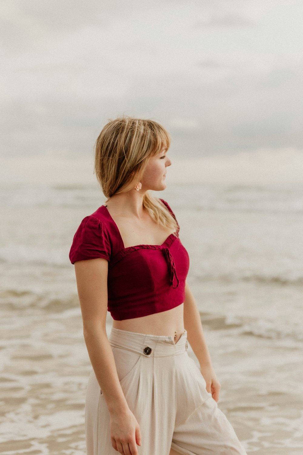Foto Mujer en crop top rojo y pantalones cortos de mezclilla blanca de pie  en la playa durante el día – Imagen Marrón gratis en Unsplash