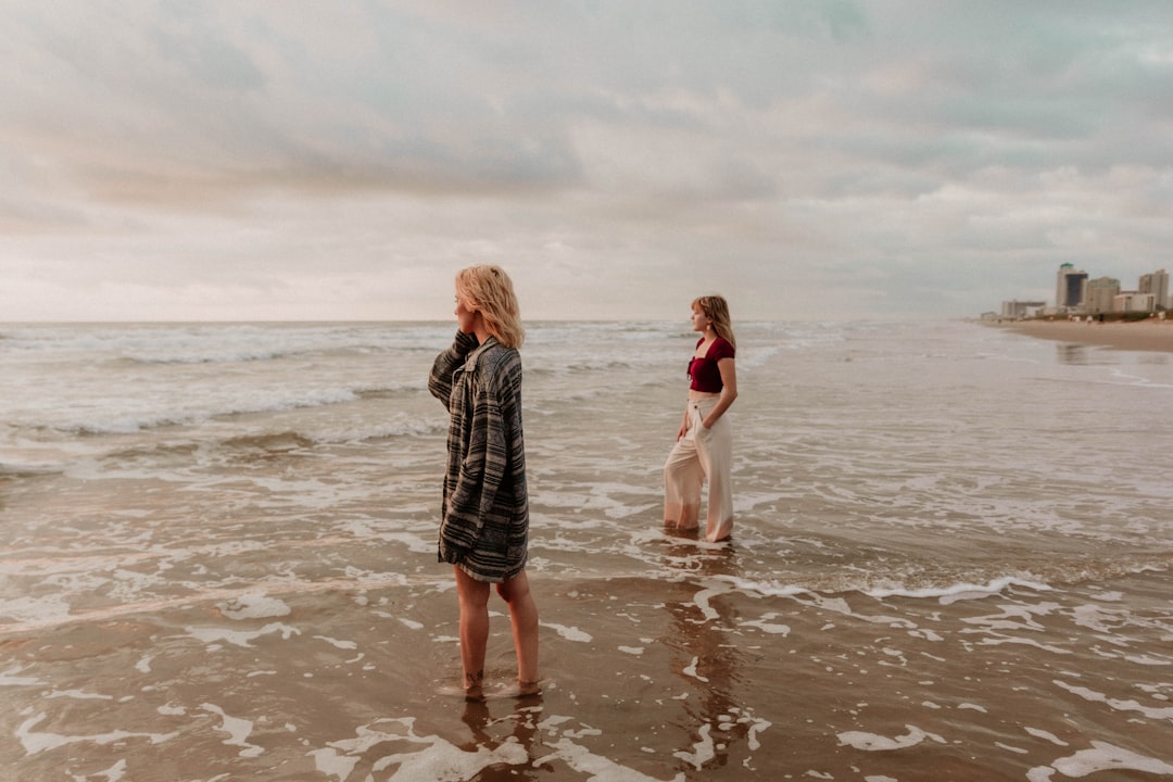 2 girls walking on beach during daytime