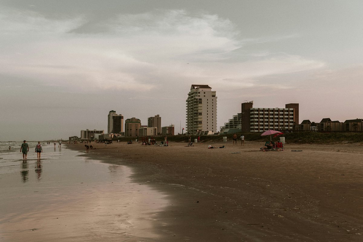 People walking a wide beach with condos behind