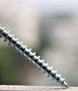 Close-up of a golden screw tightly securing a large industrial metal roof.