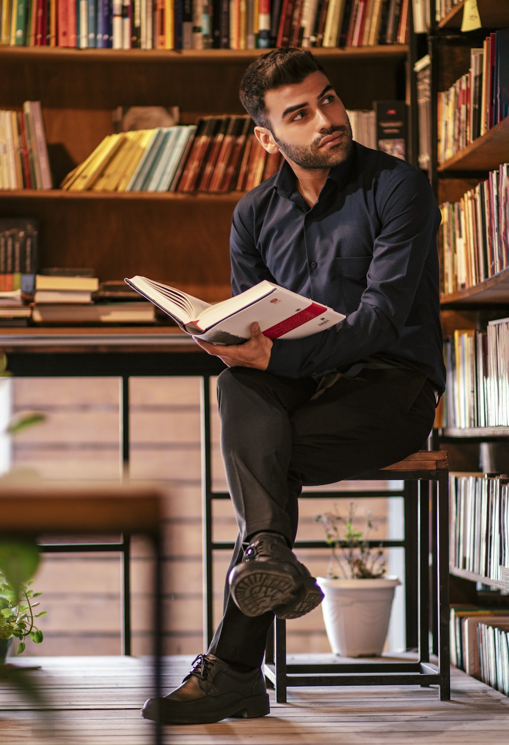 man in black dress shirt holding white book