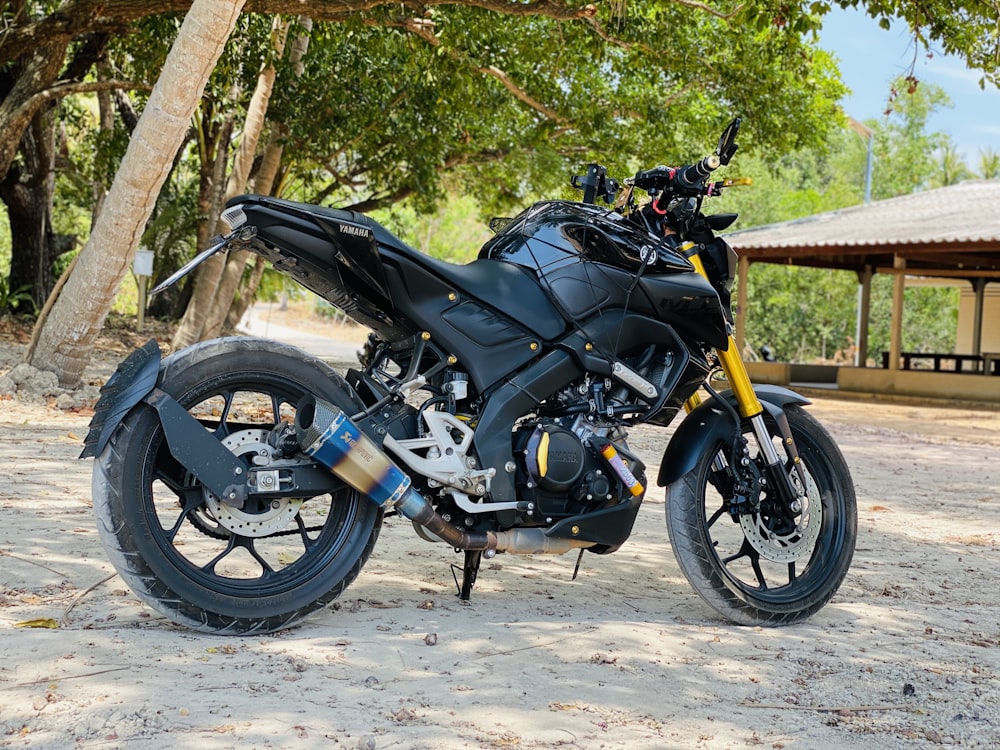 black and yellow motorcycle parked near brown wooden fence during daytime