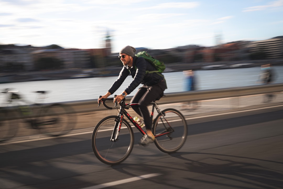 man in black jacket riding on black bicycle on road during daytime