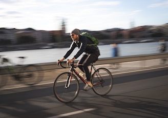 man in black jacket riding on black bicycle on road during daytime