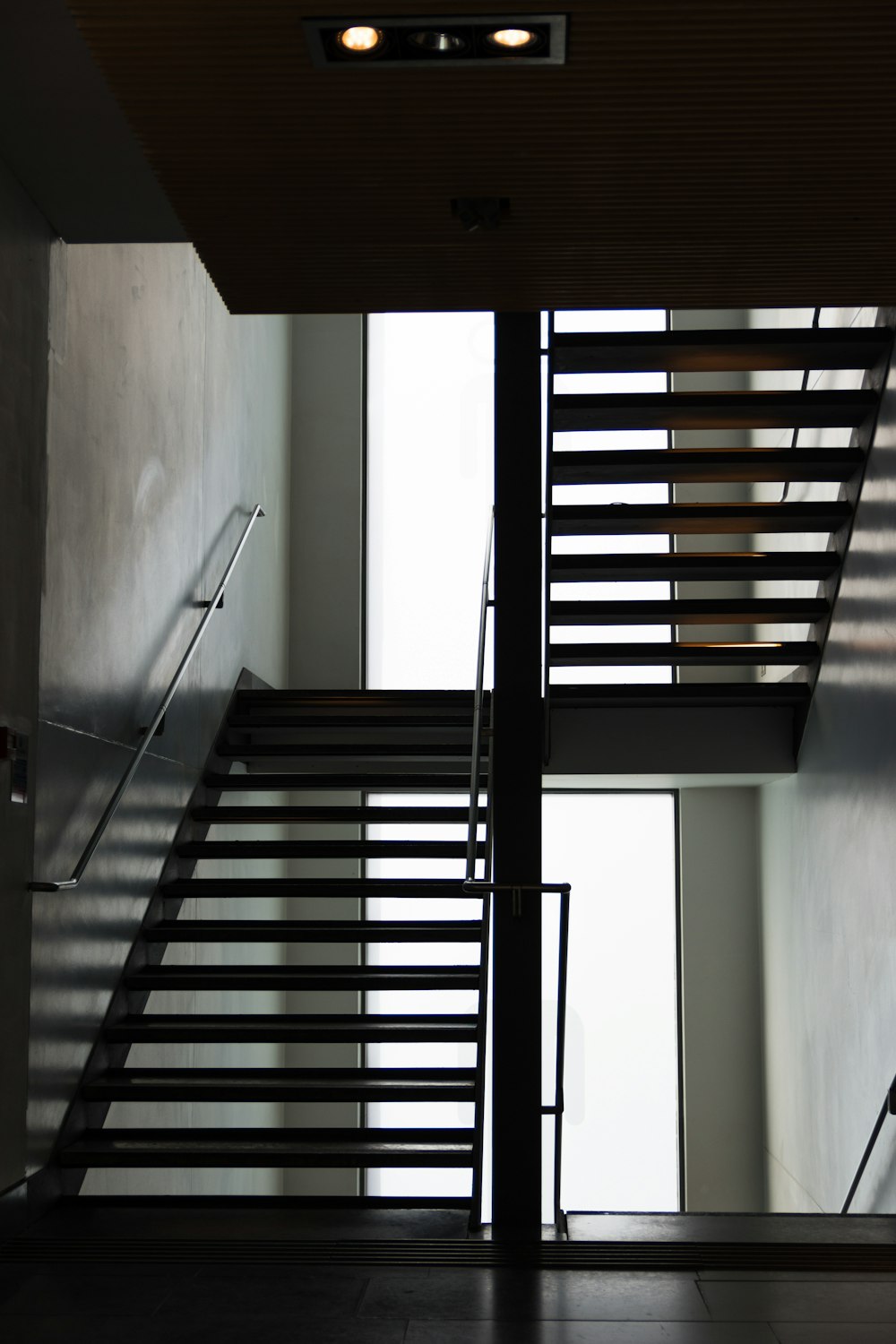 Escalier en bois noir près du mur blanc