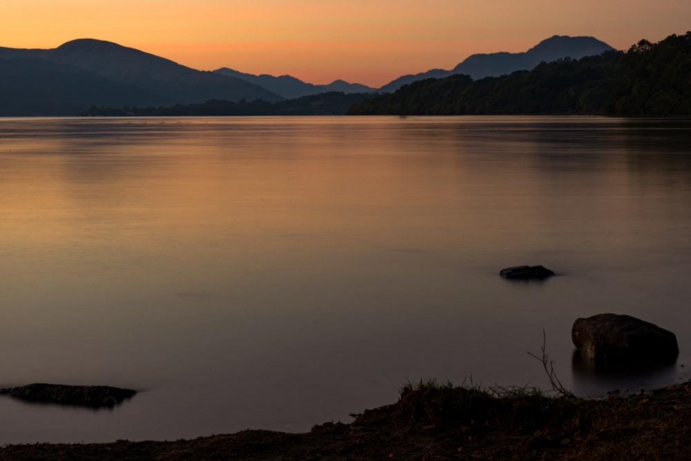 body of water near mountain during daytime