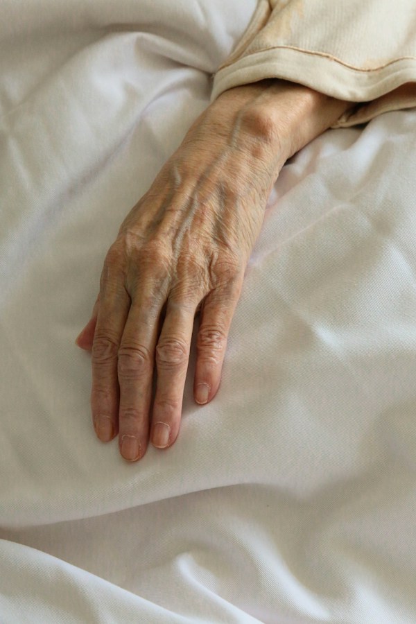 Caregiver holding the hand of a hospice patient, representing compassionate end-of-life care