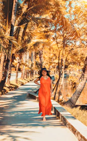 Model walking on a sunlit street wearing a comfortable, flowy tropical outfit in shades of orange.