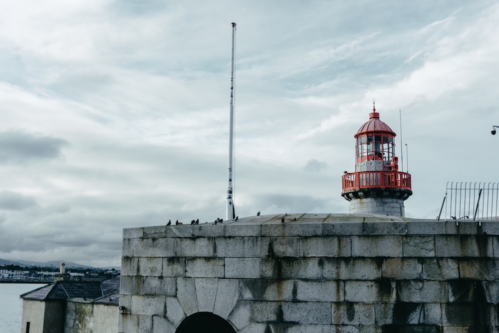 Faro rojo y blanco bajo nubes blancas durante el día