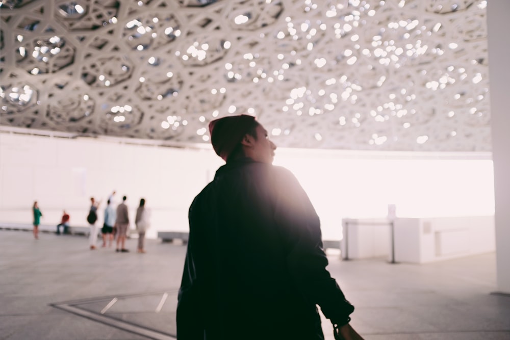 man in black jacket walking on gray concrete floor