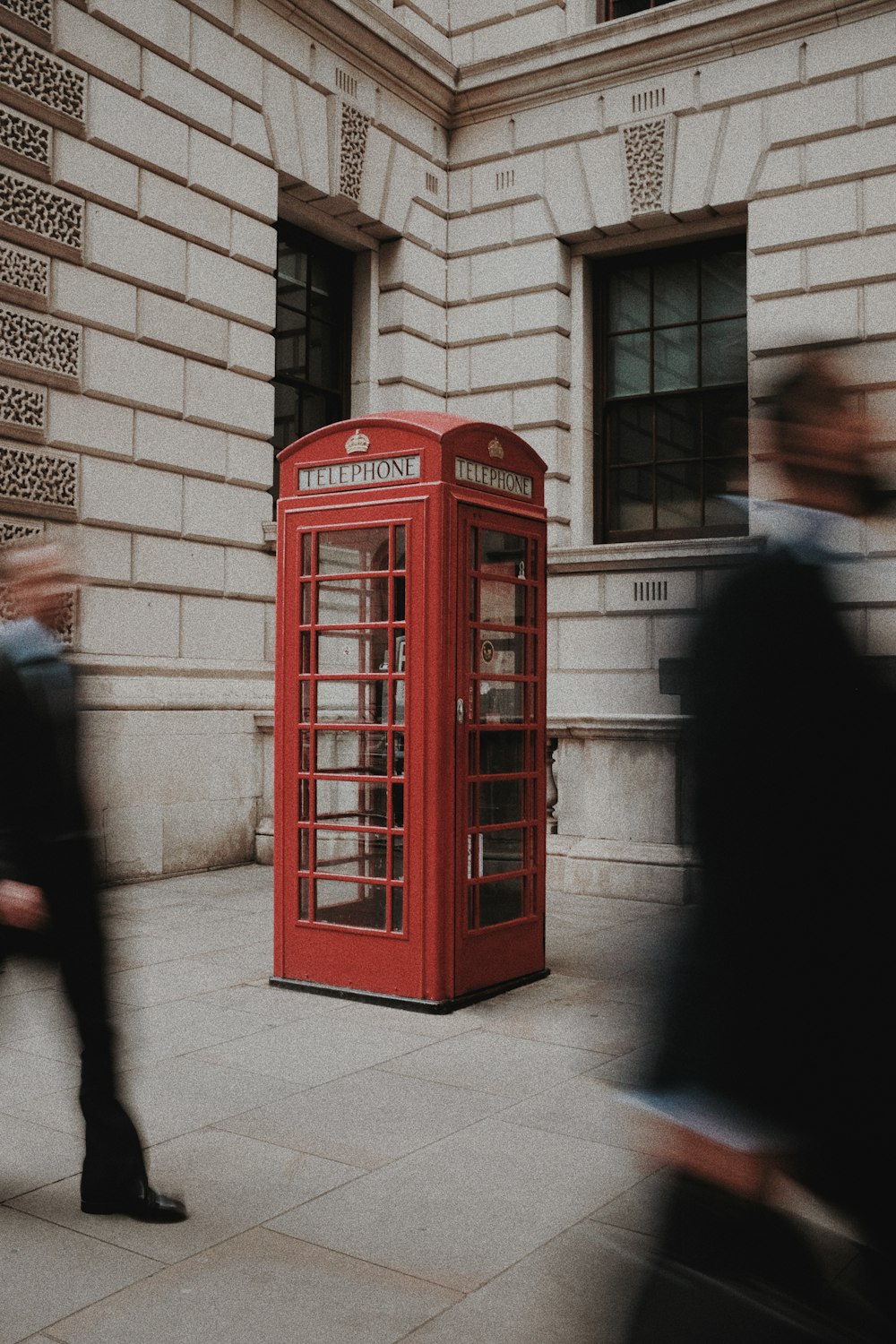 red telephone booth beside brown brick wall