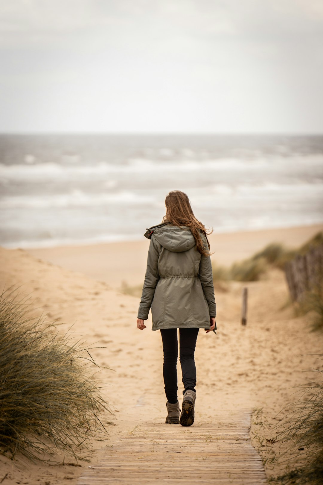 woman in brown coat standing on brown sand during daytime