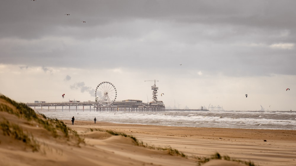 white ferris wheel on brown sand near body of water during daytime