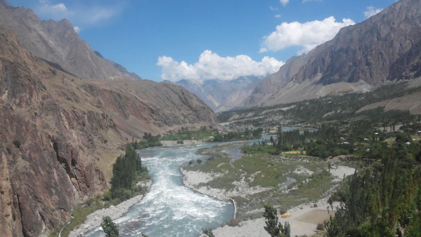 A serene river winding through lush green valley under a clear blue sky.