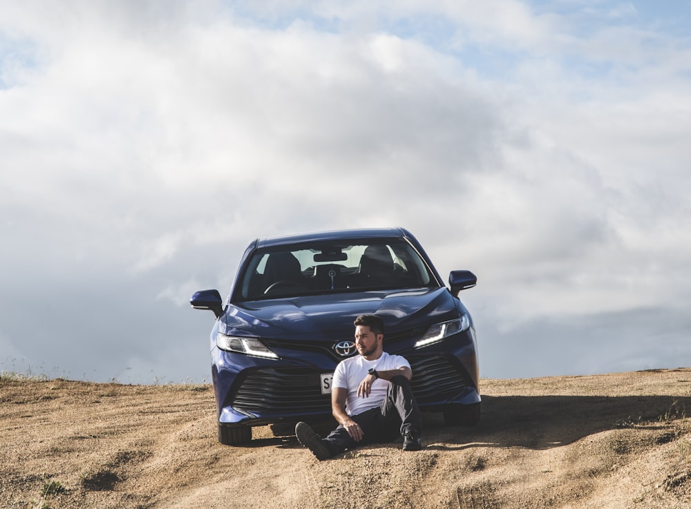 man in white t-shirt sitting on black car