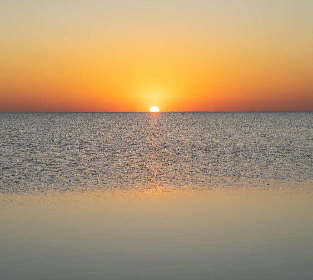 calm sea under orange sky during sunset