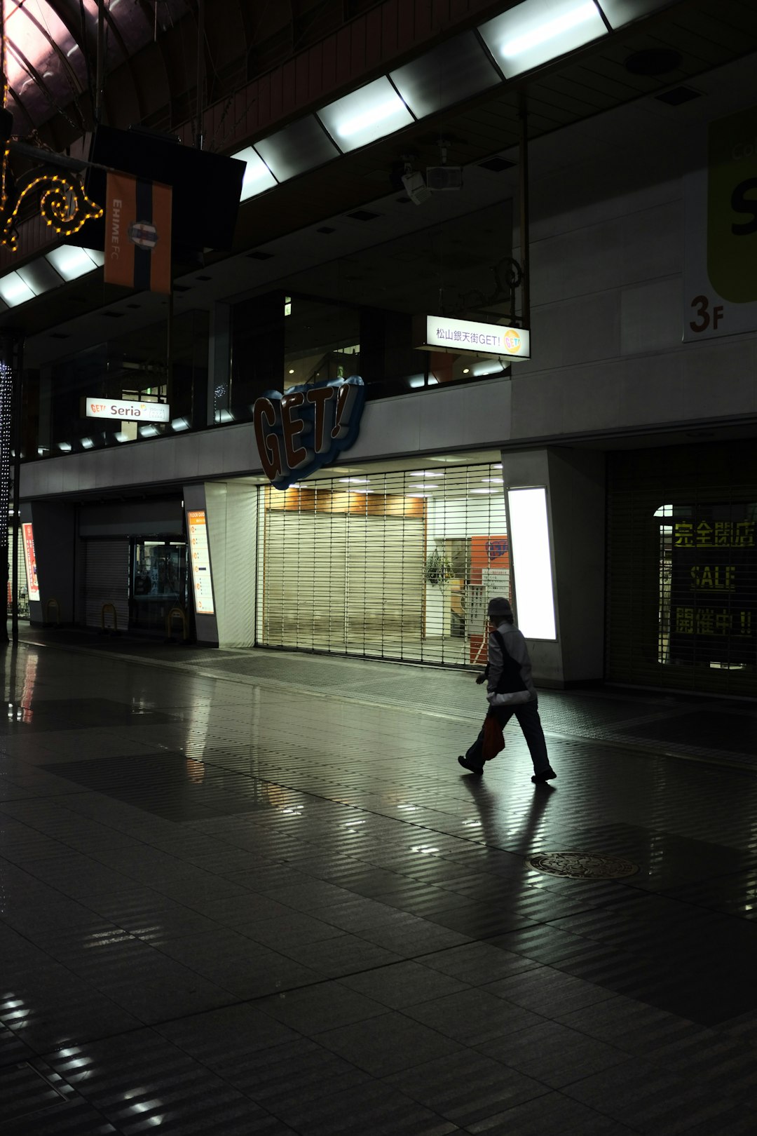 woman in black jacket walking on gray floor tiles