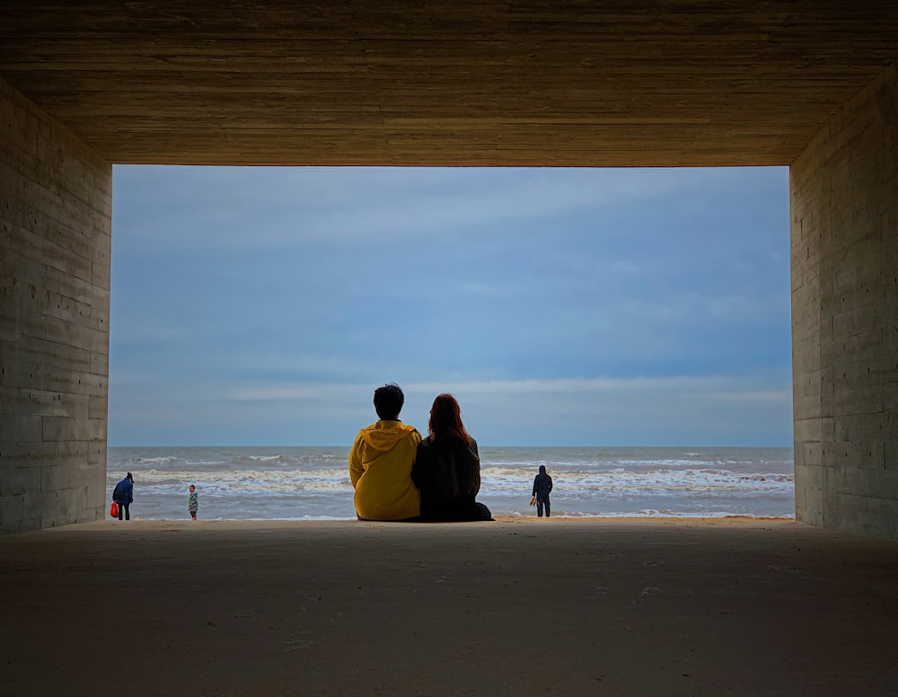 man and woman sitting on beach during daytime