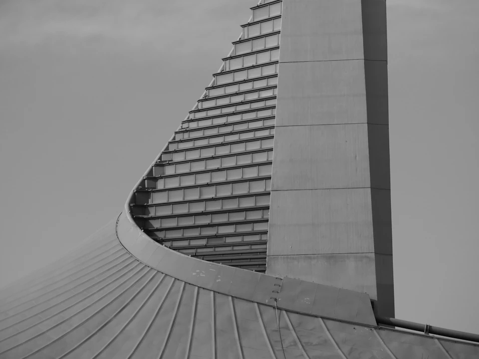 Large, curved concrete structure with multiple levels and pointed top dominates the skyline