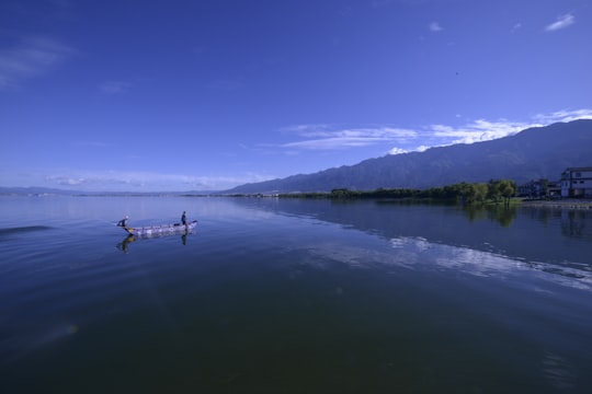 person riding on boat on lake during daytime in Dali China