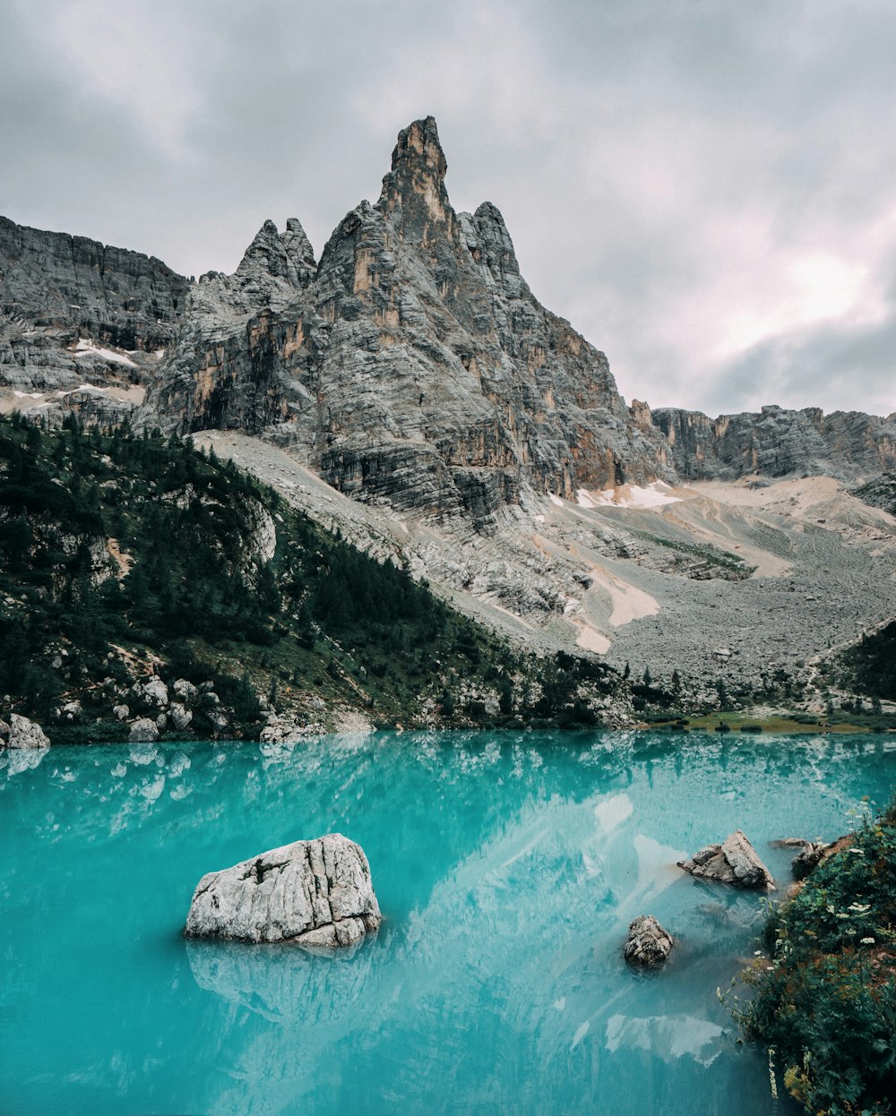 gray rocky mountain beside blue body of water during daytime