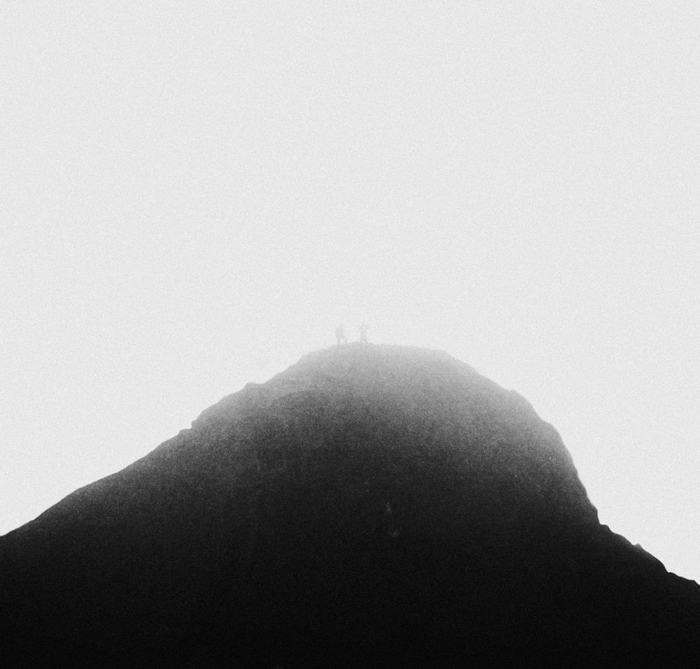 silhouette of person standing on rock formation during daytime