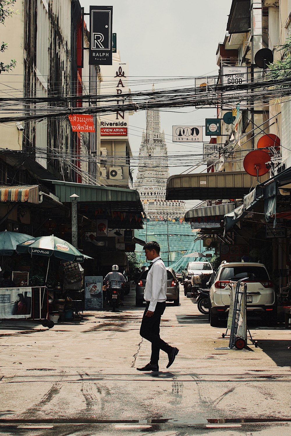 man in white dress shirt and black pants walking on sidewalk during daytime