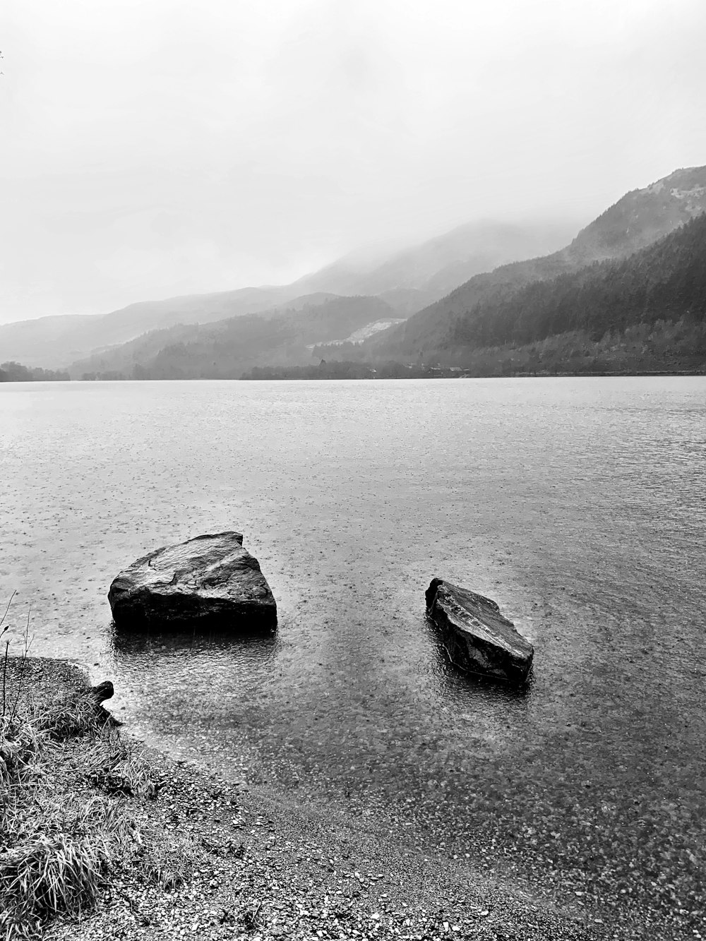 grayscale photo of rock formation on body of water