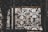 Intricate wrought iron patterns form ornate designs with floral and circular motifs. The metalwork features a rustic, aged appearance, with light filtering through behind, highlighting the craftsmanship.