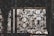Intricate wrought iron patterns form ornate designs with floral and circular motifs. The metalwork features a rustic, aged appearance, with light filtering through behind, highlighting the craftsmanship.