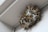 A close-up view of a paper wasp nest attached to a white surface, with numerous wasps tending to the nest cells. The nest consists of hexagonal paper-like cells, and the wasps have distinct yellow and brown stripes.