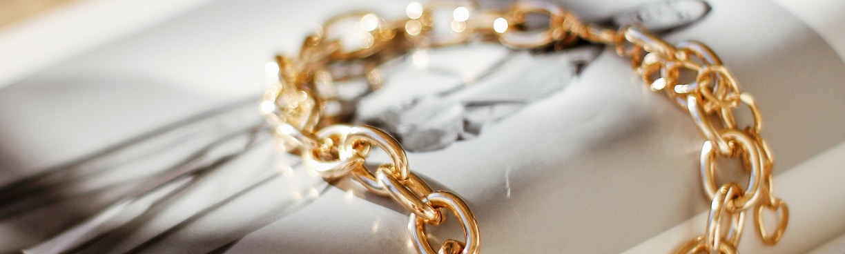 a gold chain bracelet sitting on top of a magazine