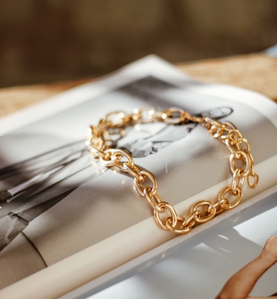 a gold chain bracelet sitting on top of a magazine