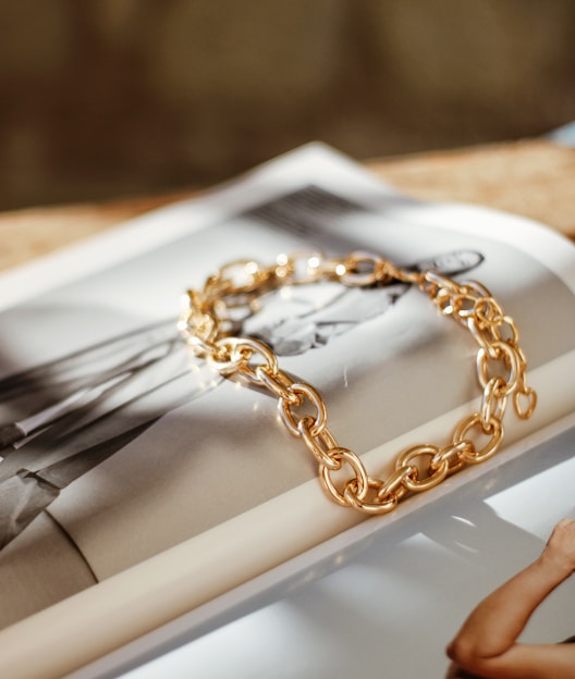 a gold chain bracelet sitting on top of a magazine